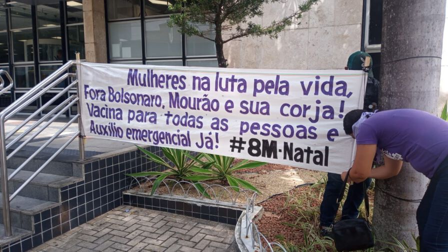 Faixa do dia internacional de luta das mulheres, onde se lê "Mulheres na luta pela vida, Fora Bolsonaro, Mourão e sua corja! Vacina para todas as pessoas e Auxílio emergencial já! #8M Natal"